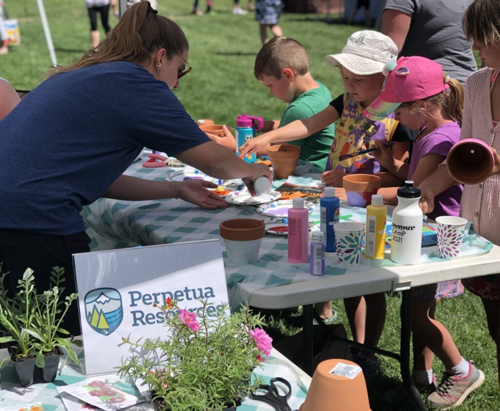 Perpetua Resources team member helping children plant flowers at a community event